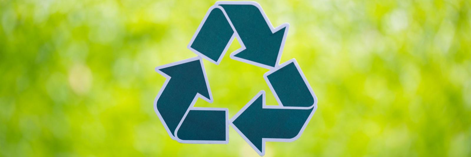 Ver- & Entsorgung beim Facility Management Recyclingsymbol bestehend aus drei Pfeilen, die sich im Uhrzeigersinn drehen im gruenen Hintergrund