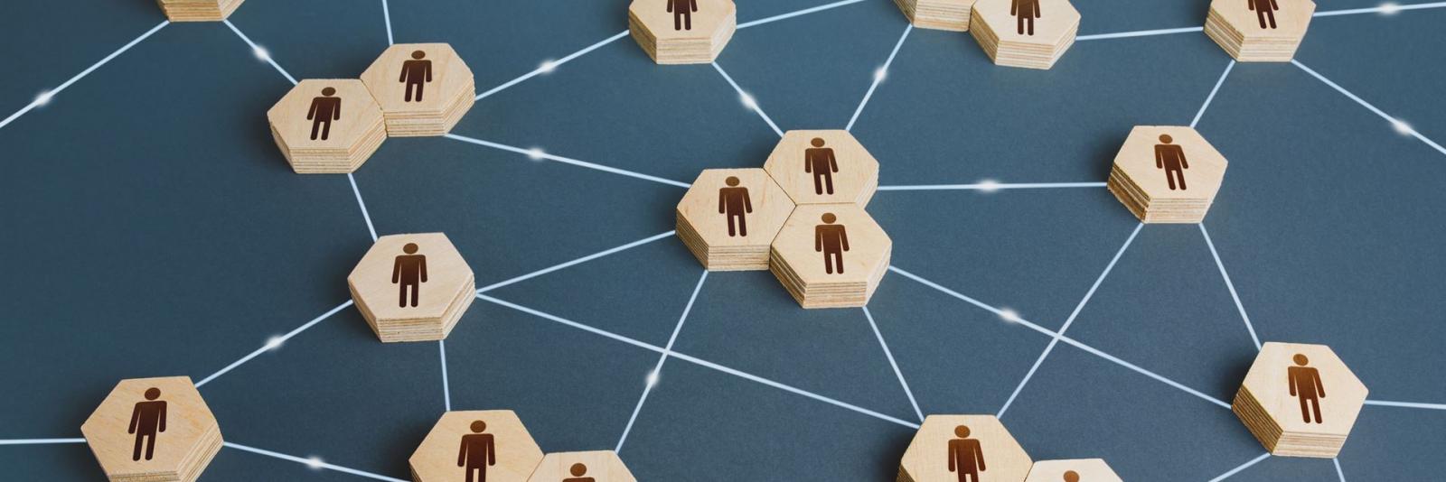 Koordination - Facility Management Sechseckige Figuren aus Holz mit Menschen-Zeichen und durch weisse Faeden miteinander verbunden
