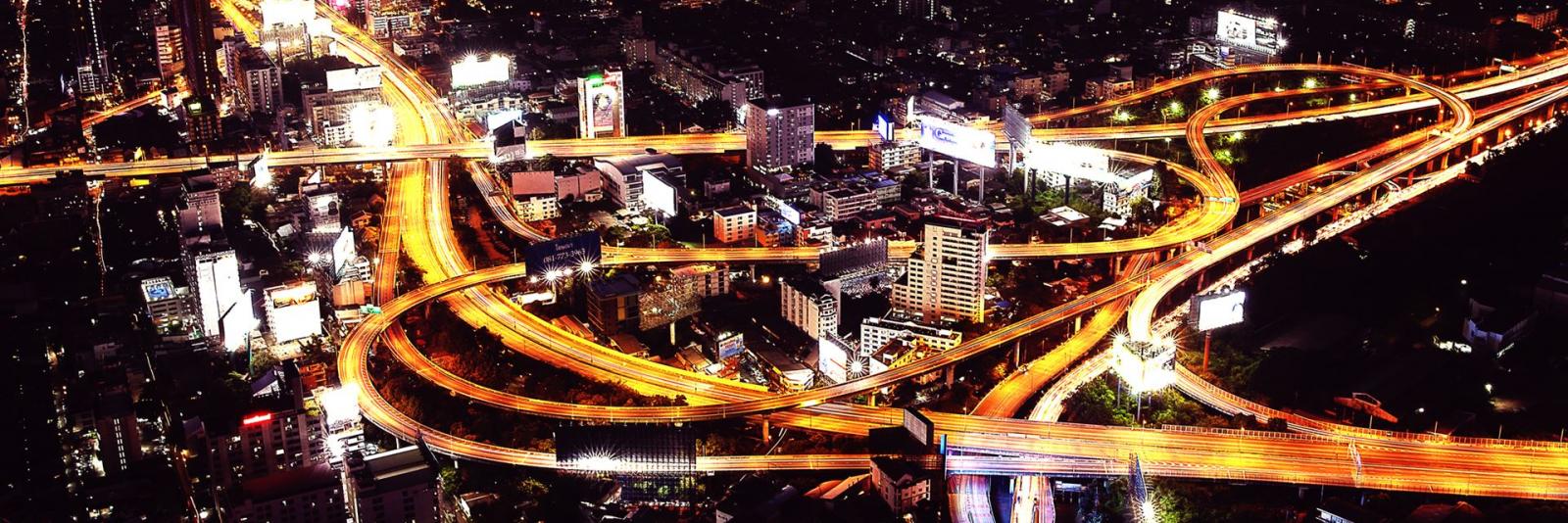 Mobilität – Facility Management Naechtliche Luftaufnahme der Autobahn & Stadtgegend in Bangkok, Thailand