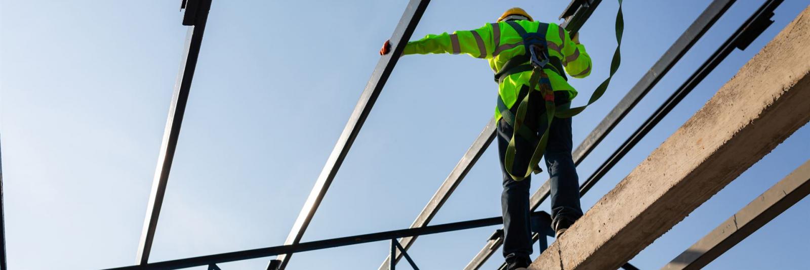 Einhaltung der Gesundheitsschutzanforderungen beim Facility Management Arbeiter auf einer Baustelle ueber einen Auffanggurt gesichert