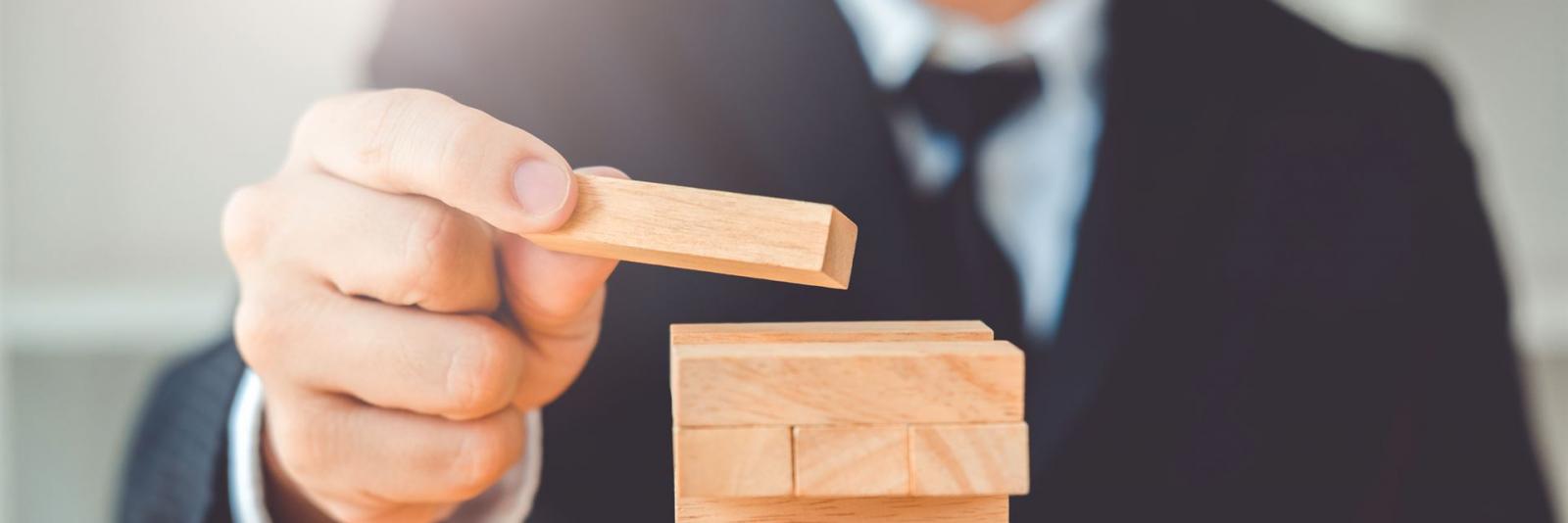 Planung der Implementierung des FM Expert sitz sorgfaeltig ein Jenga-Bauteil auf den Turmkopf auf