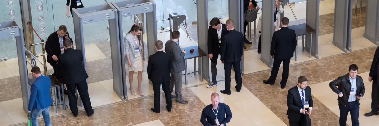 Sicherheitsdienste am Büroarbeitsplatz – Facility Management Mitarbeiter einer Firma werden mit Durchgangsdetektoren und Sicherheitspersonal kontrolliert