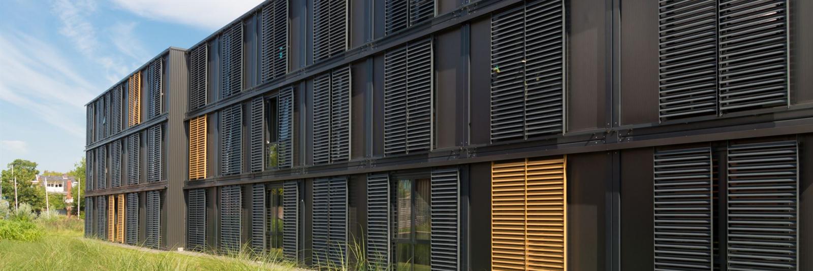 Konzeption von Betreibermodellen im Bereich Facility Management Ansicht eines Buerogebaeudes mit Raffstores und Holzlamellen in schwarz und braun