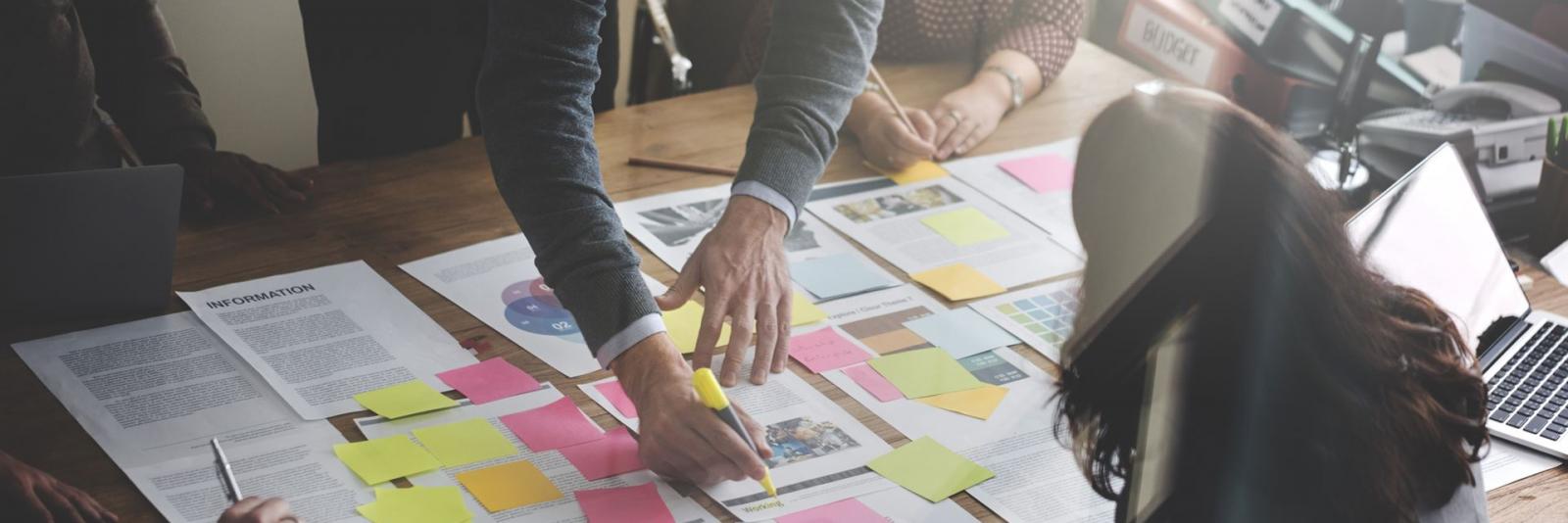 Gestaltung von Nutzungskonzepten beim Facility Management Experten diskutieren und planen am Konferenztisch mit Hilfe von Berichtsseiten, Haftnotizen und Laptops